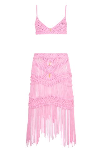 A two-piece pink macramé set consisting of a bralette-style top and a high-waisted, fitted skirt. The skirt features intricate woven patterns and long fringe details, creating a delicate and stylish look.