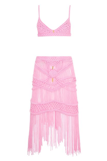 A two-piece pink macramé set consisting of a bralette-style top and a high-waisted, fitted skirt. The skirt features intricate woven patterns and long fringe details, creating a delicate and stylish look.