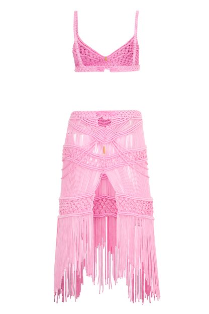 A two-piece pink macramé set consisting of a bralette-style top and a high-waisted, fitted skirt. The skirt features intricate woven patterns and long fringe details, creating a delicate and stylish look.