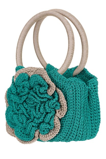 A handmade macramé handbag in green and beige, featuring a large front flower design and two round handles.